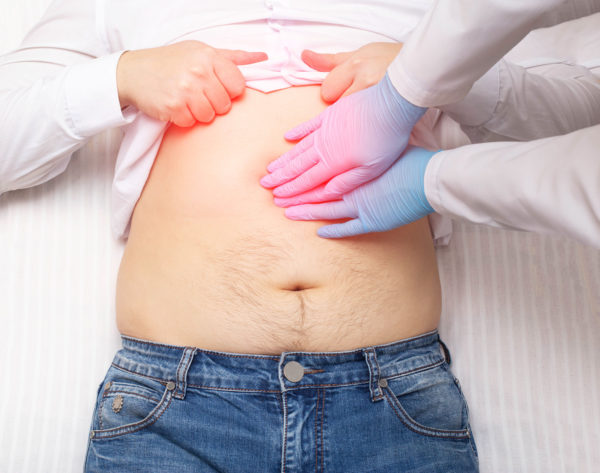 The doctor examines a patient who has abdominal pain. Pancreas inflammation concept, pancreatitis, close-up. Inflammation of the gallbladder and duodenum