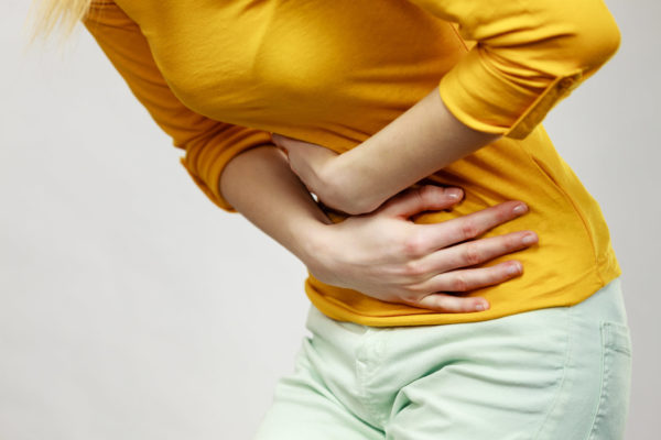 Woman suffer from belly pain. Health care concept. Bellyache, indigestion or menstruation. Young female suffering from strong stomach ache abdominal pain on gray